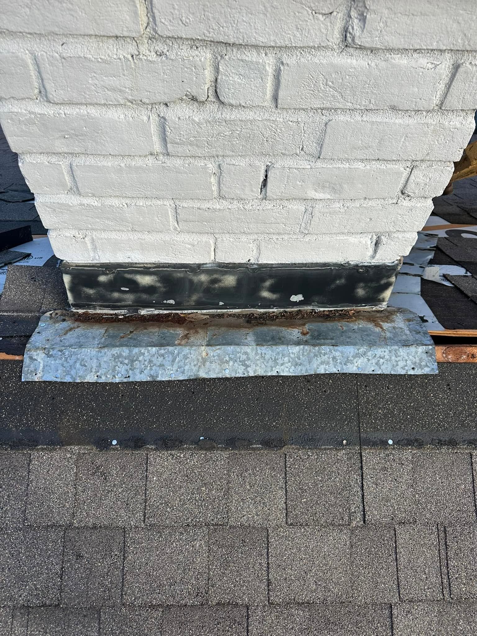 Close-up of a cinder block wall base with dark flashing and a blue-gray ledge over gravel.