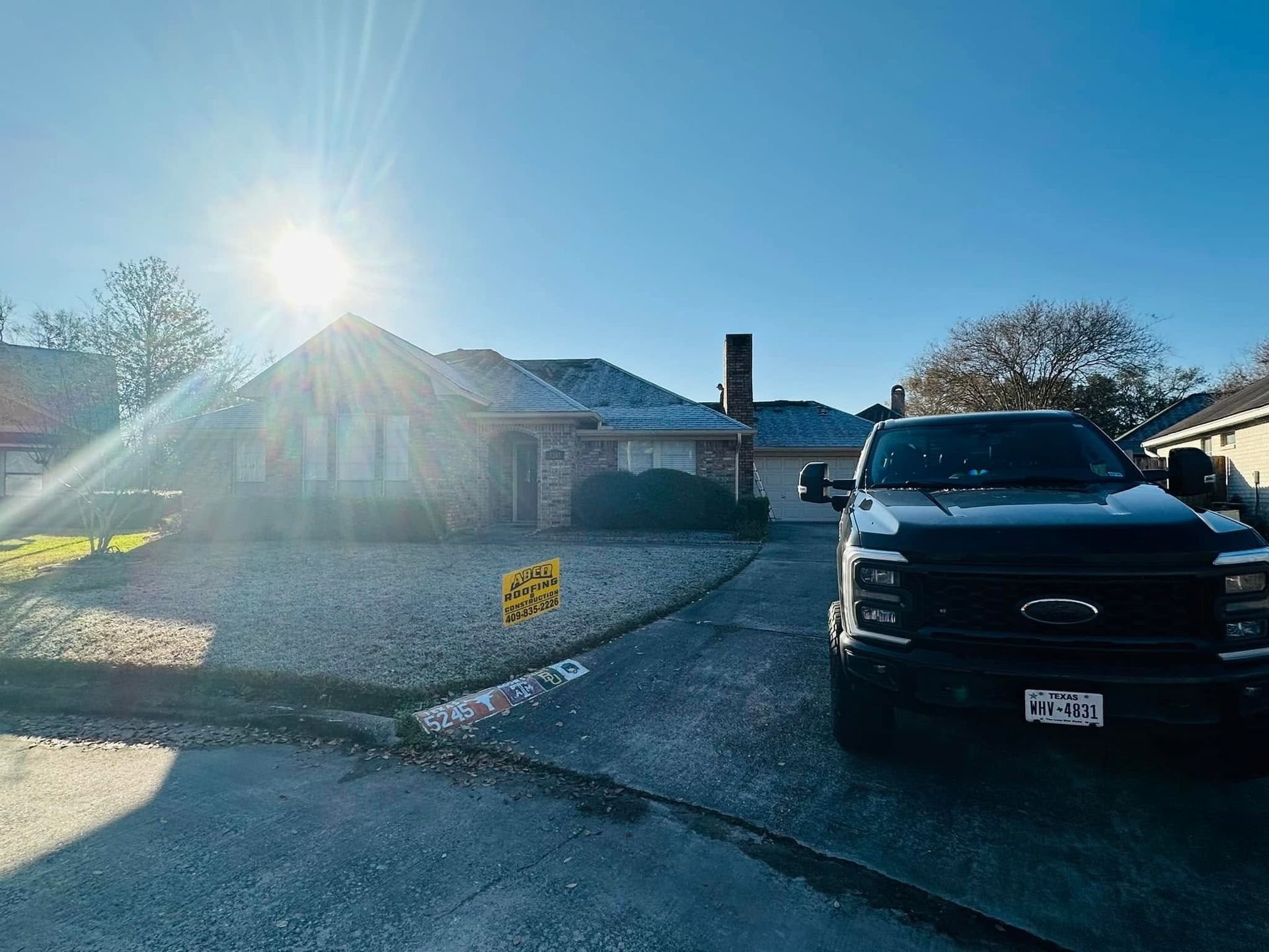Sunlit suburban house with a black truck parked in the driveway