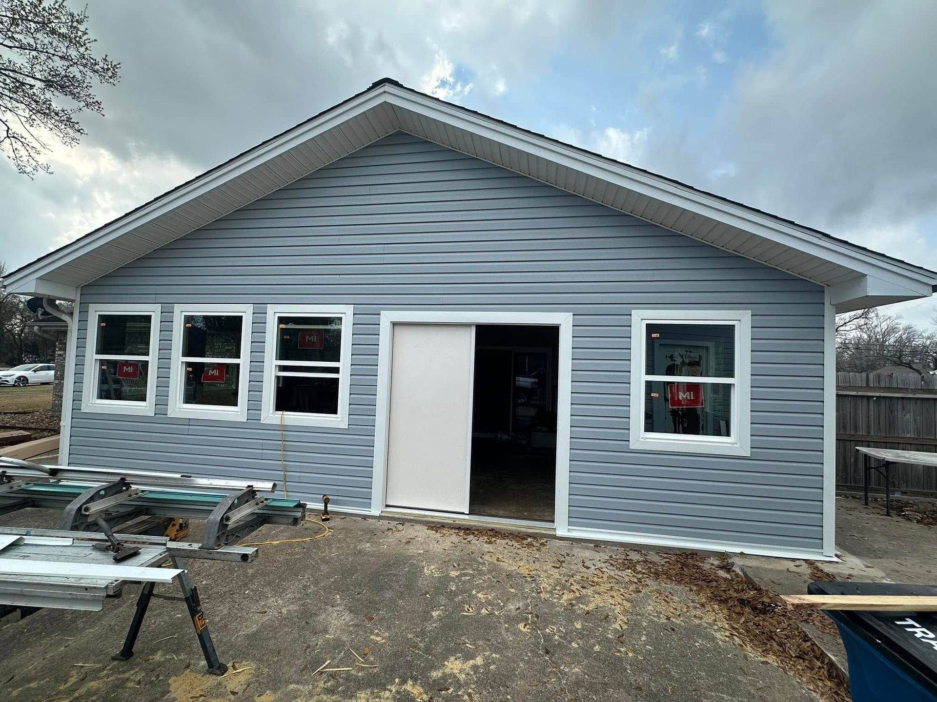 Single-story gray house under construction with white trim and an open front door