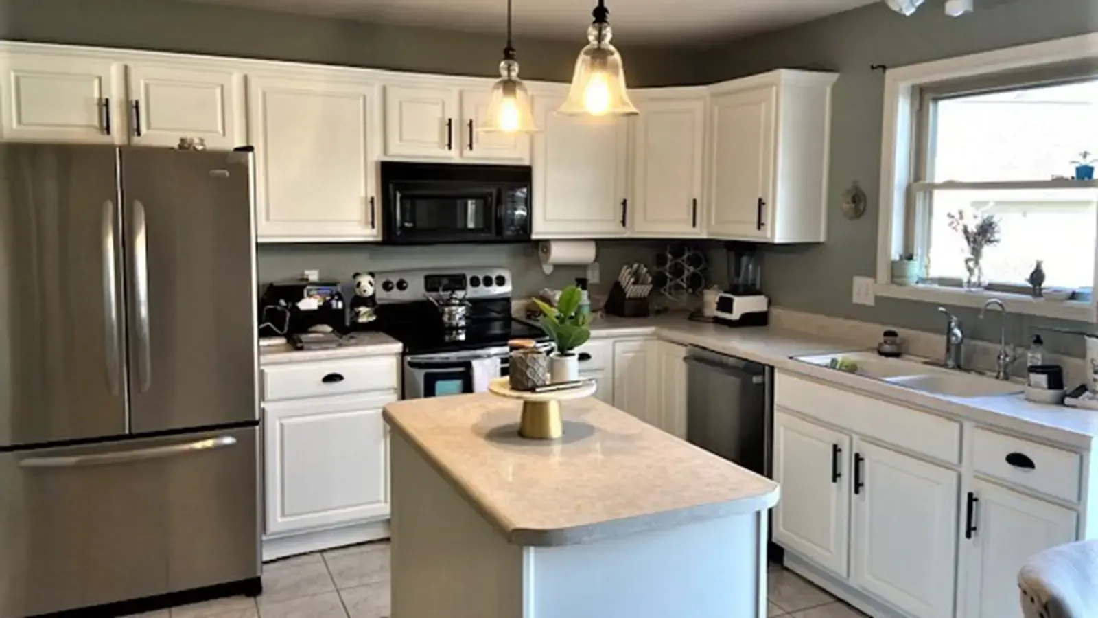 White kitchen with stainless steel appliances, white cabinets, and a kitchen island.