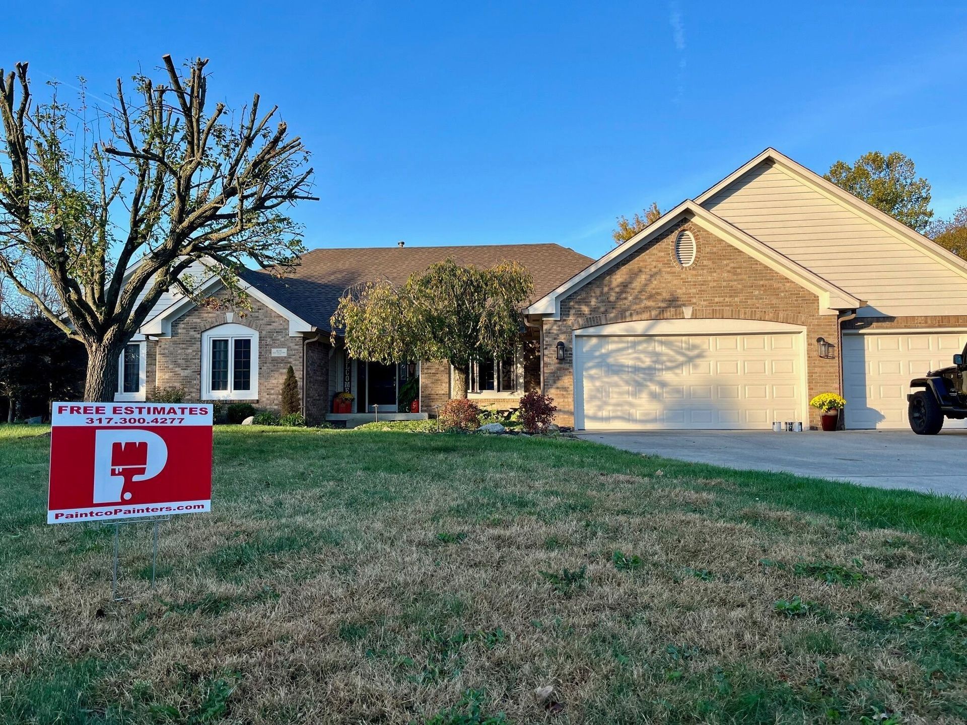 House with lawn, a sign in front with a red 