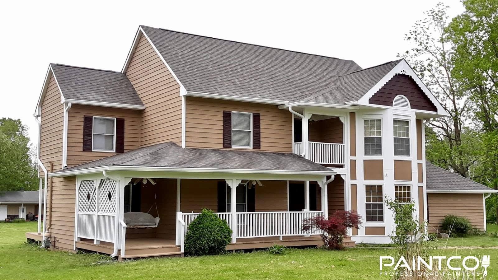 Two-story house with brick siding, brown trim, white porch, and green lawn.