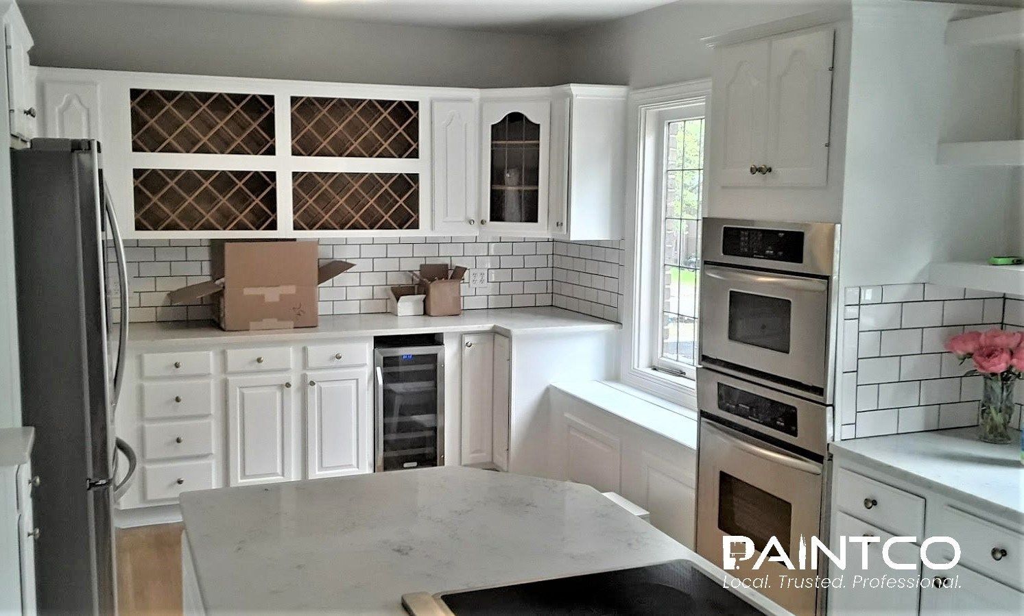 White kitchen with cabinets, subway tile backsplash, stainless steel appliances, and wine rack.