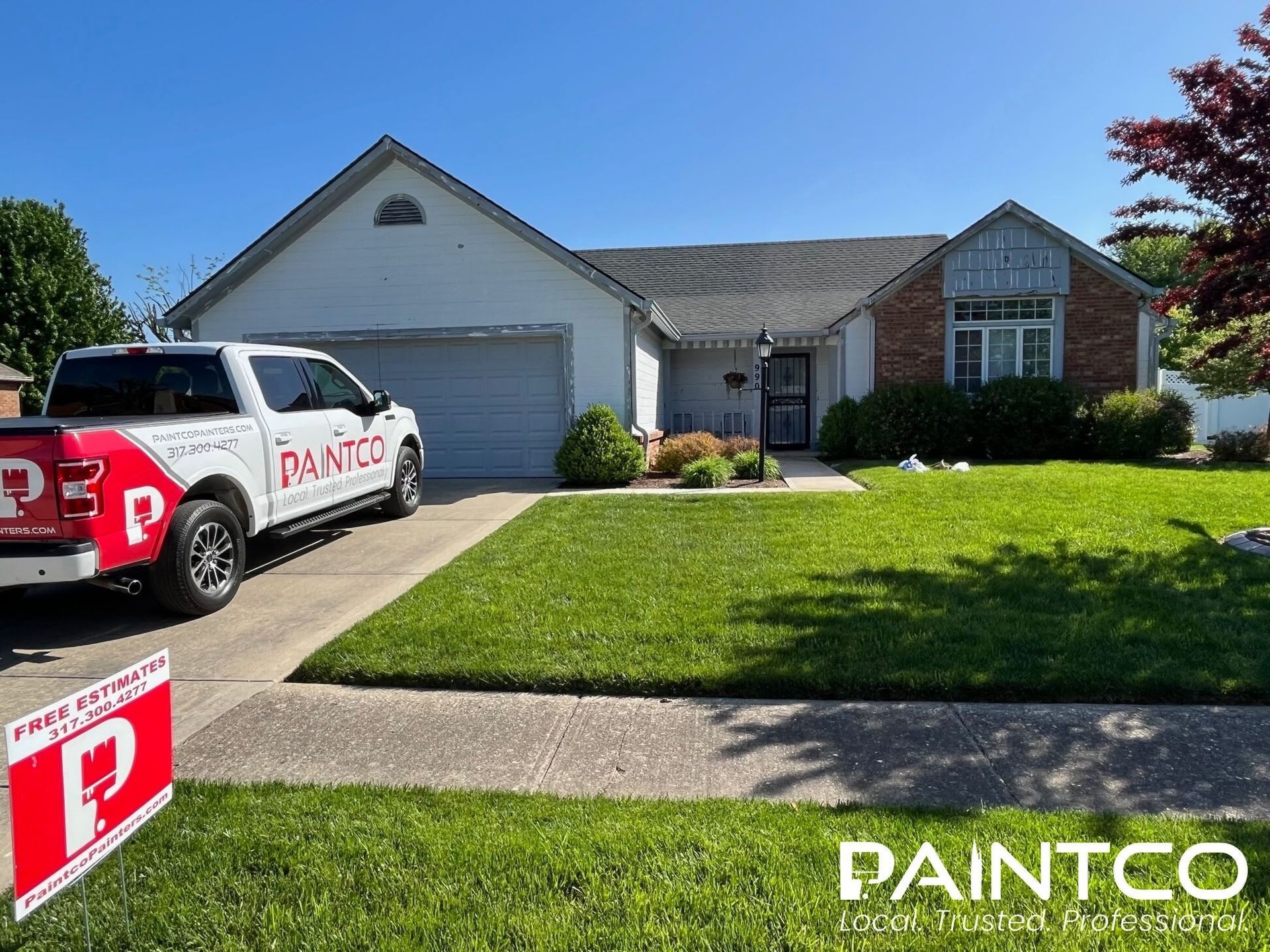 A white truck with PAINTCO logo parked in front of a house; a sign offers free estimates.