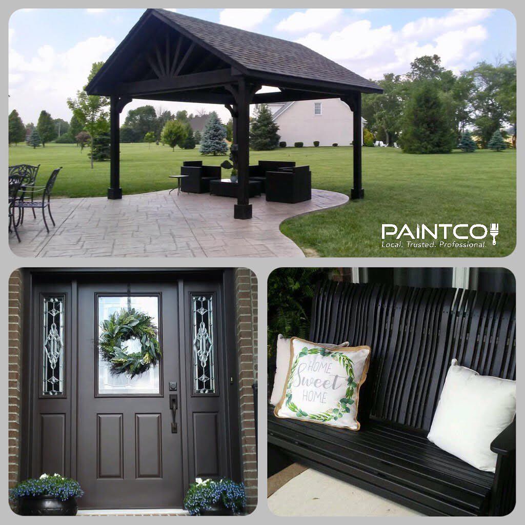 Black-painted outdoor structures: gazebo, door, and porch swing, set in a yard with green grass.
