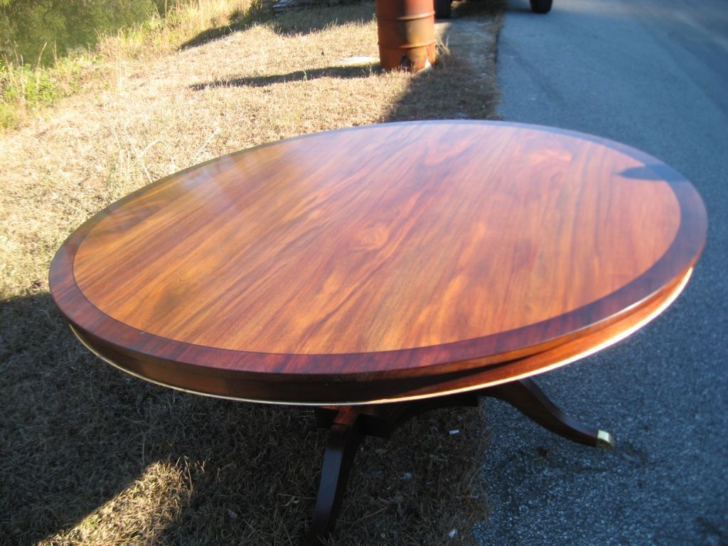 Round wooden table with dark brown wood top and a contrasting border, set outside on grass.