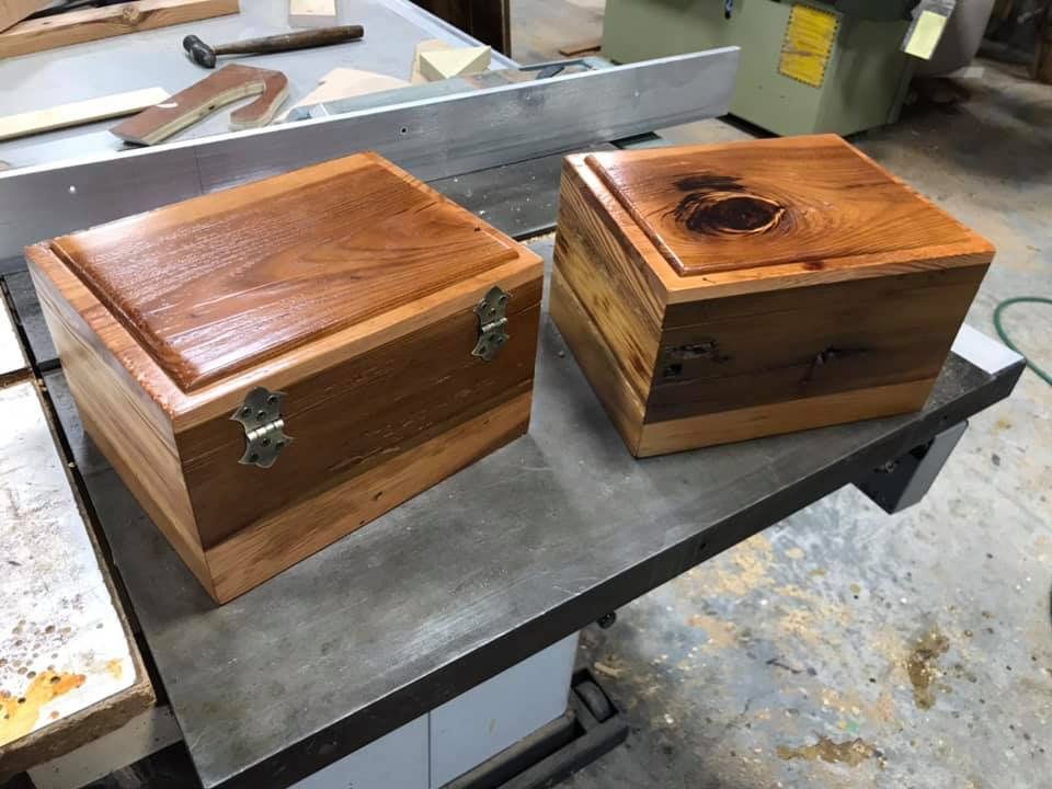 Two wooden boxes with lids on a silver table saw.