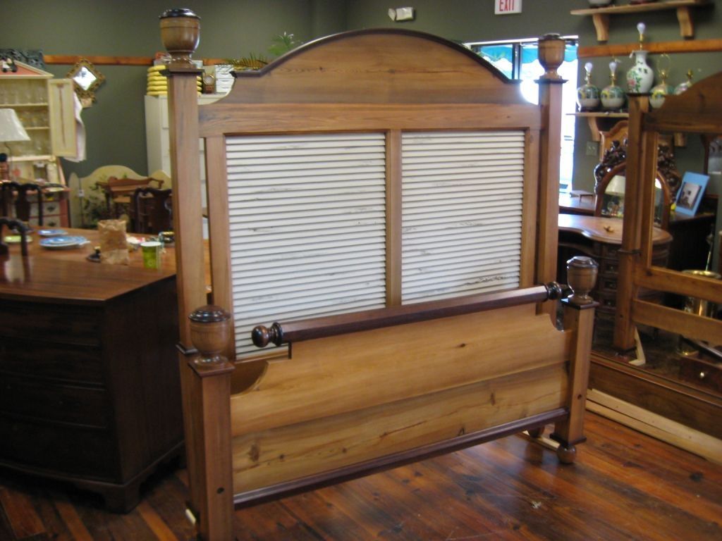 Wooden bed frame with a headboard made of slats, displayed in a furniture store.