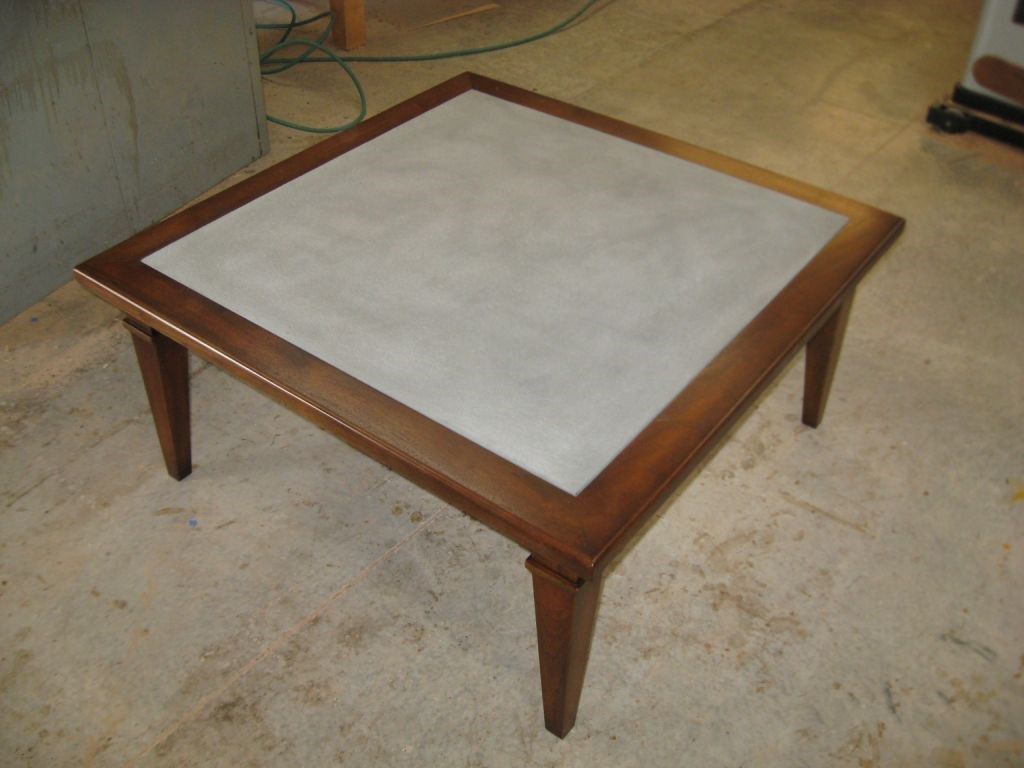 Square coffee table with a gray center and brown wooden frame and legs.