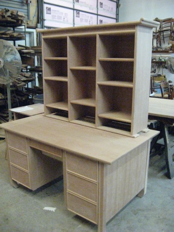 Wooden desk with hutch. Shelves on top, drawers on the sides. Unfinished, in a workshop.