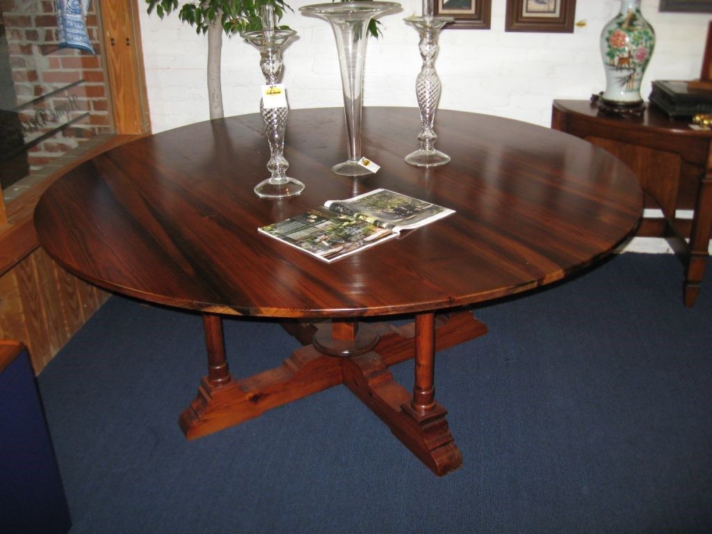 Round wooden dining table with ornate legs, featuring two crystal candlesticks and a vase.