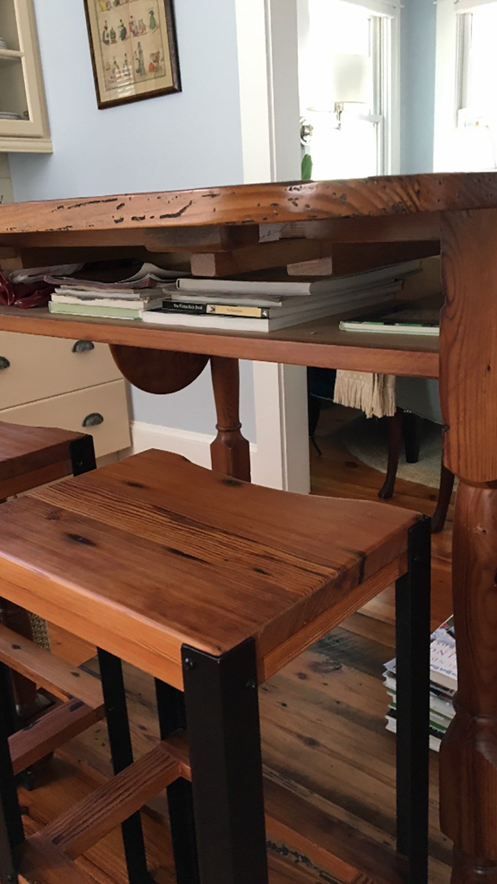 Rustic wood bar with two stools, books on shelf, and drawers in the background.