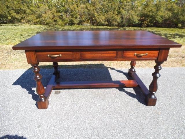 Wooden desk with two drawers, brown finish, ornate legs, outdoors.