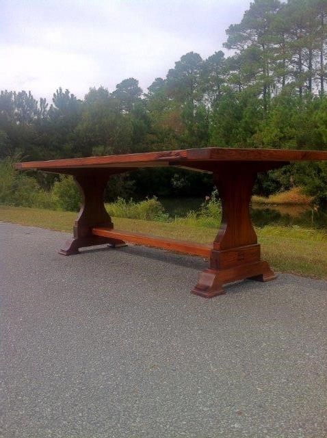 Wooden trestle table on an asphalt path, with trees and a lake in the background.