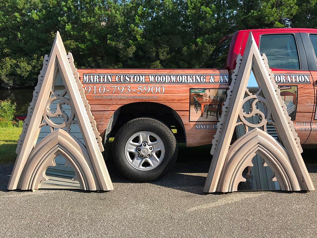 Two tan Gothic-style decorative panels leaning against a brown truck, outdoors.