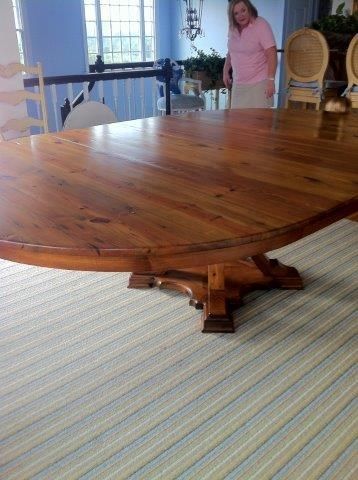 Large wooden dining table with woman standing nearby, blue walls, striped rug.