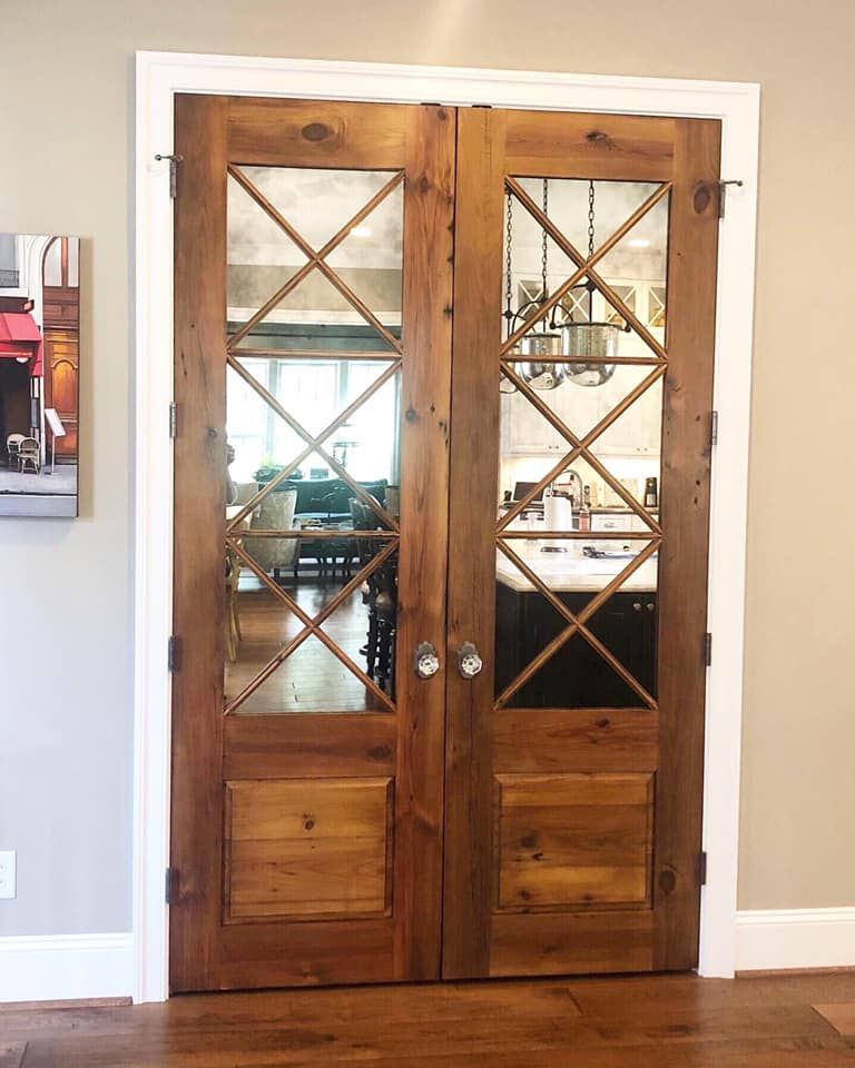 Two rustic wooden French doors with glass panes and an X-shaped grid.