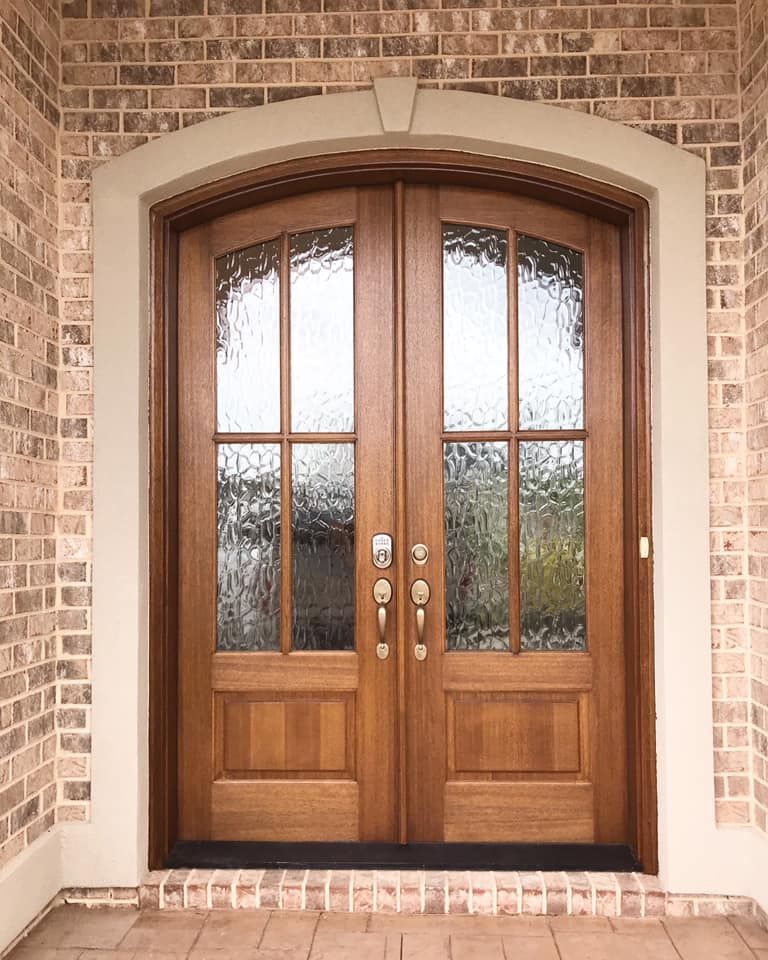 Brown double doors with glass panels and sidelight, set in a brick facade.