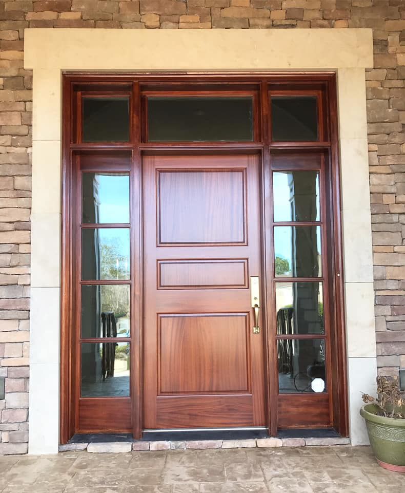 Wooden front door with sidelights and transom, set in a stone surround.