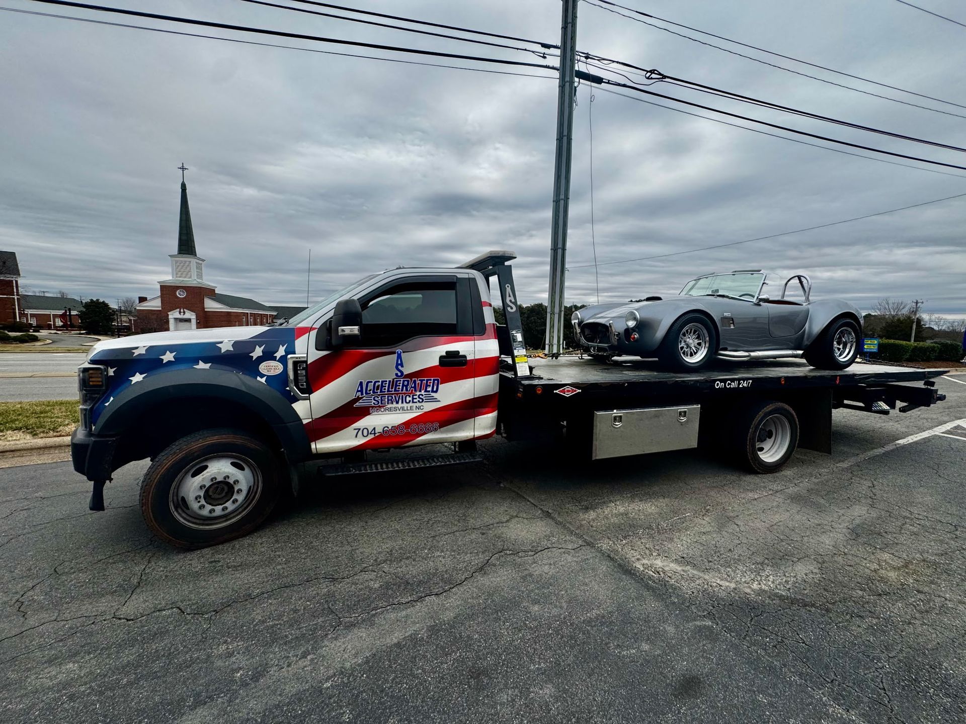 A tow truck with a car on the back is parked on the side of the road.