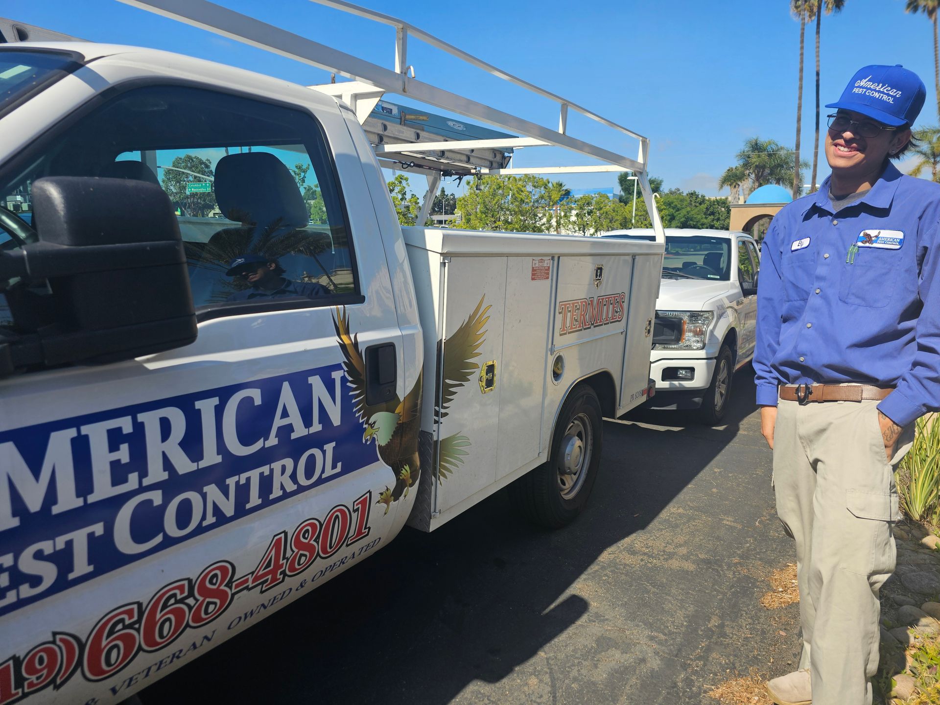 Man in uniform stands next to a pest control truck.