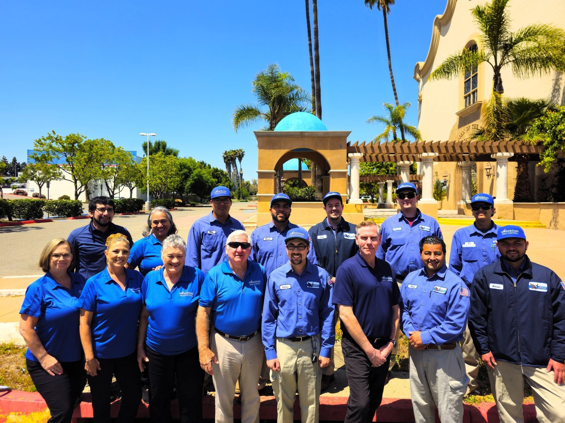 Photo of the American Pest Control team in front of their trucks with their hands up.