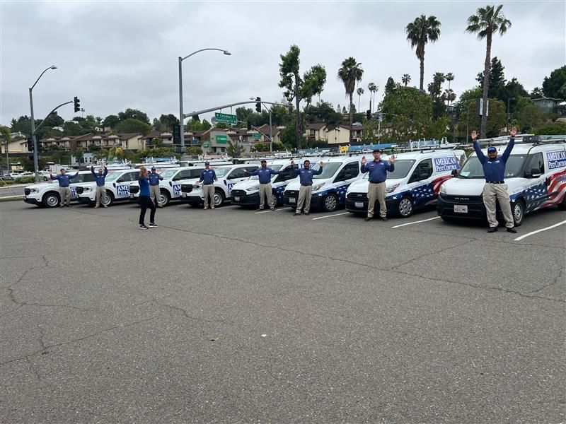 Photo of the American Pest Control team in front of their trucks with their hands up.