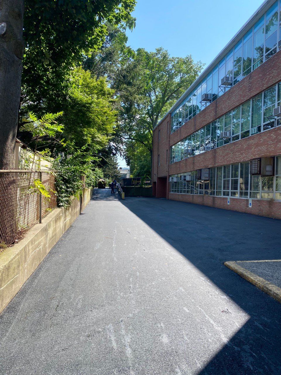A brick building with a lot of windows and trees along the side of it