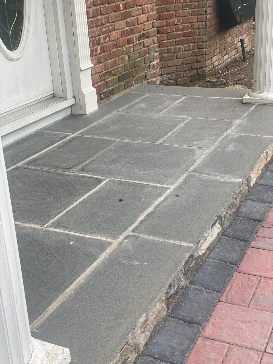 A porch with a brick wall and a statue in front of it.
