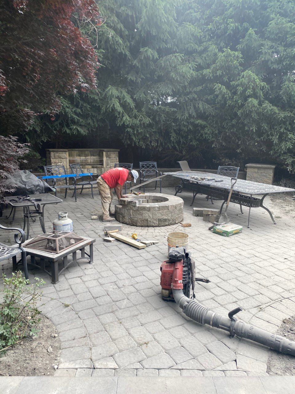 A man is working on a fire pit on a patio.