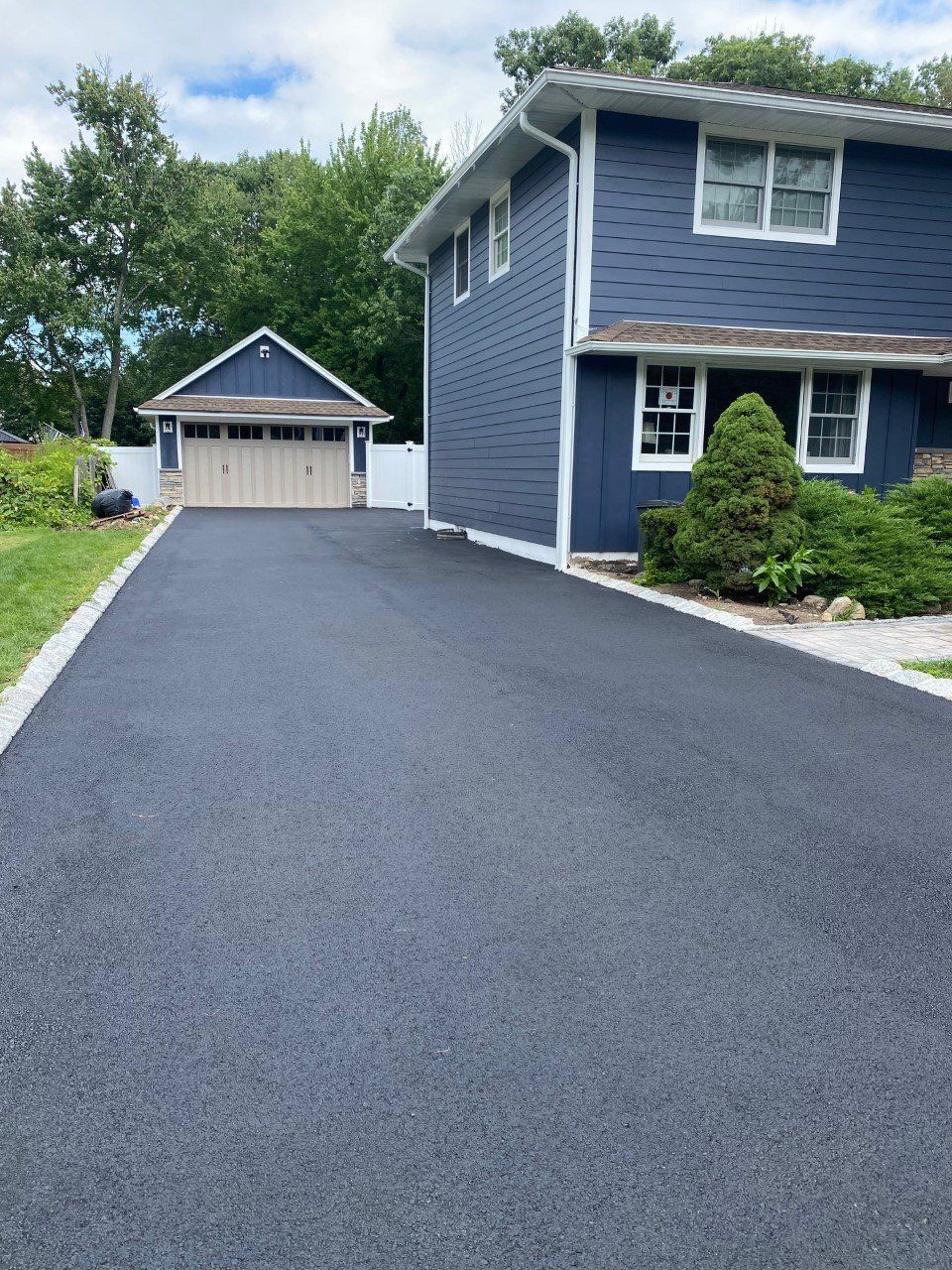 A blue house with a driveway leading to it and a garage.