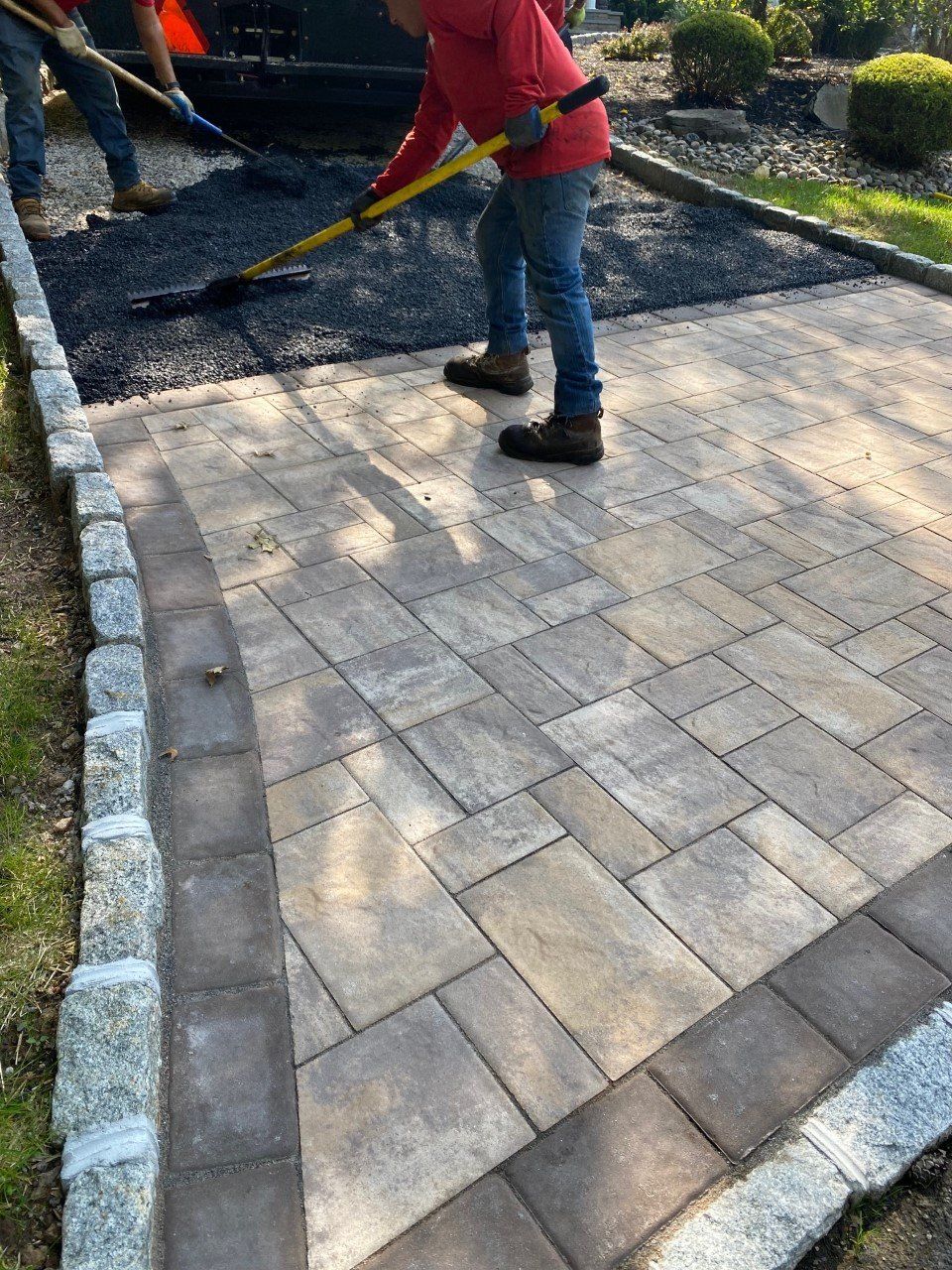 A boy is standing on a brick walkway with a broom.