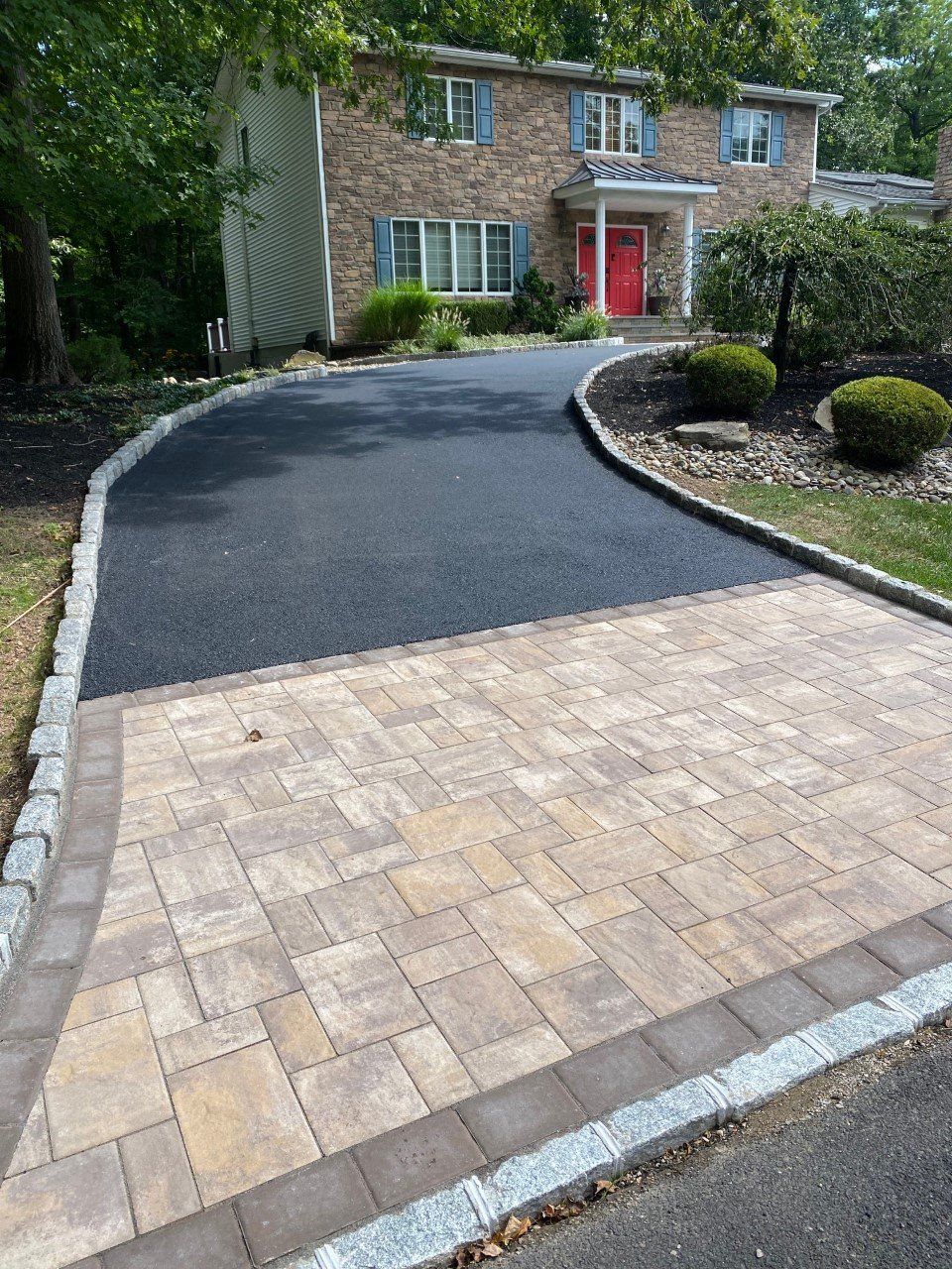 A driveway with a brick walkway leading to a house.