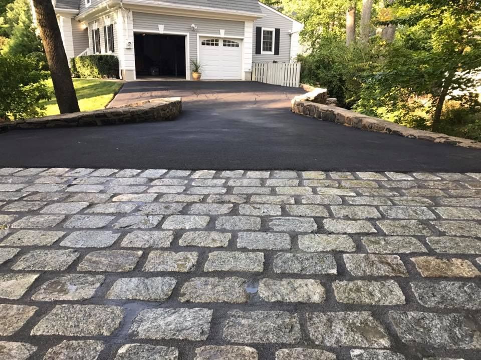 A cobblestone driveway leading to a house with a garage.