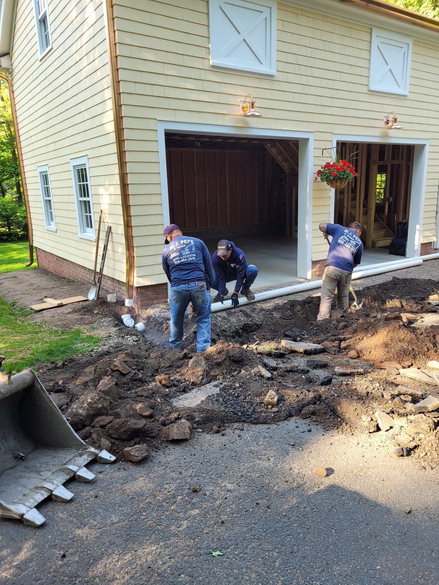A group of men are digging in the dirt in front of a garage.