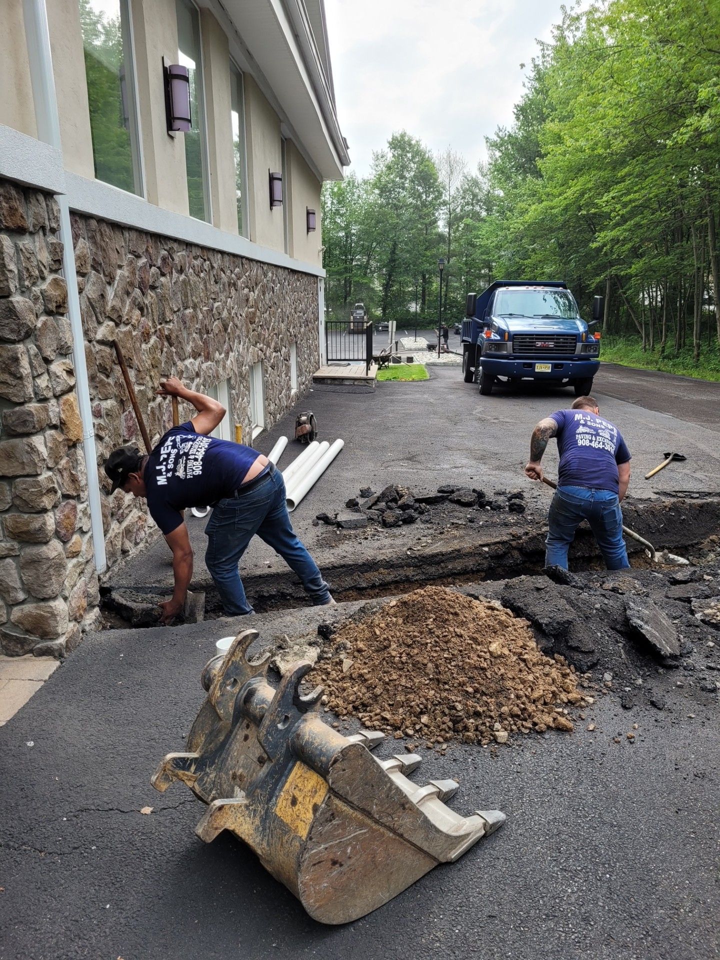 Two men are digging a hole in the ground in front of a building.