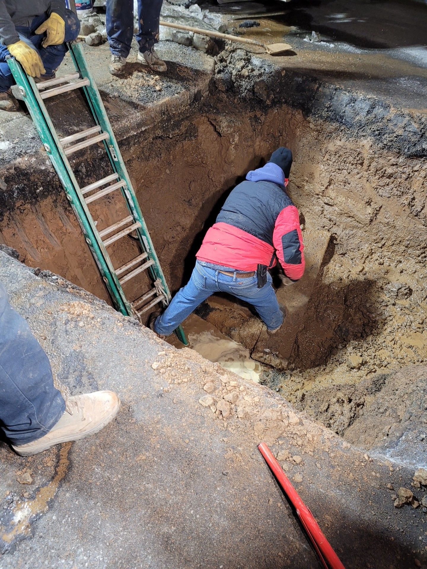A man is climbing a ladder into a hole in the ground.