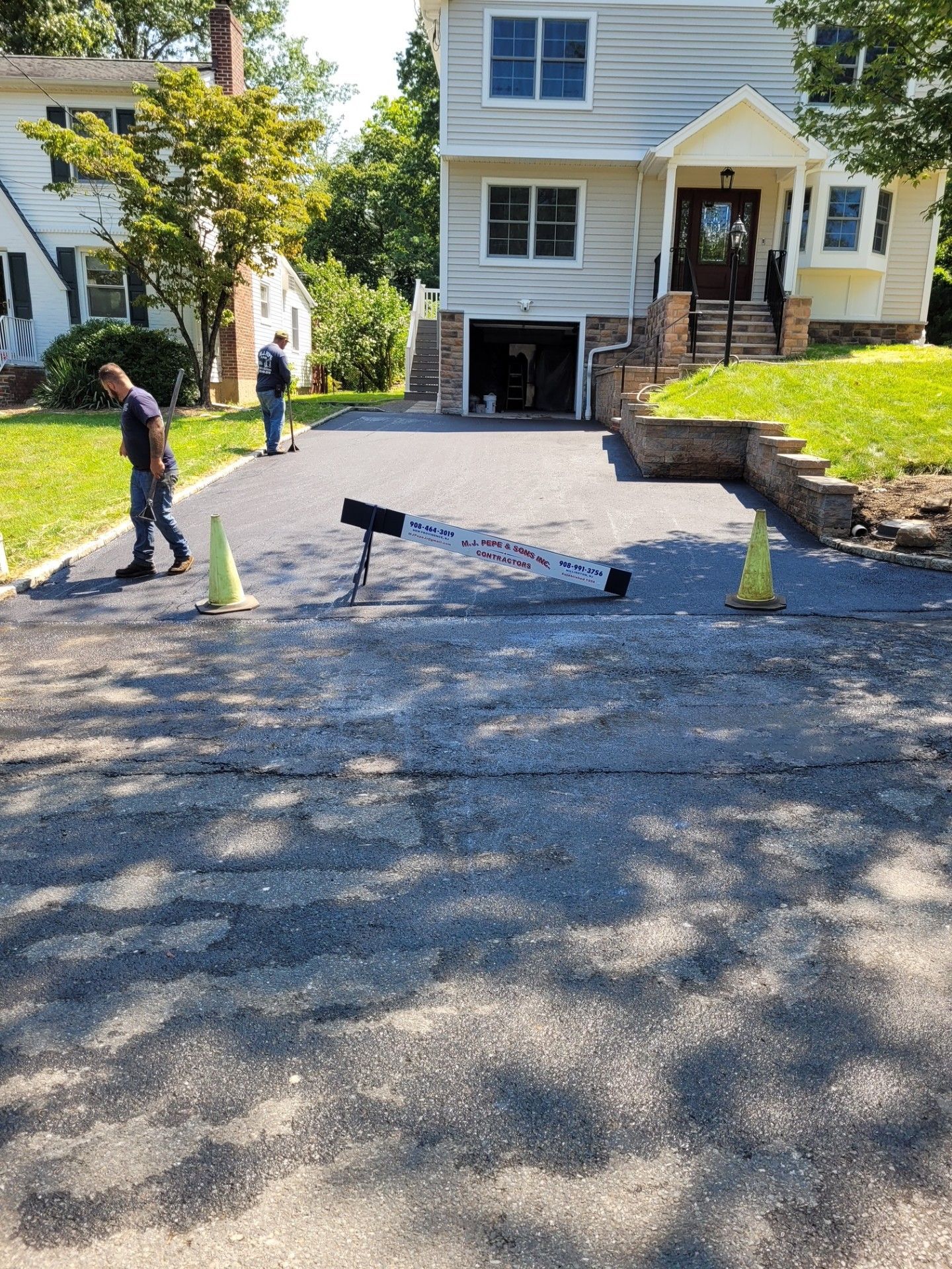 A man is working on a driveway in front of a house.