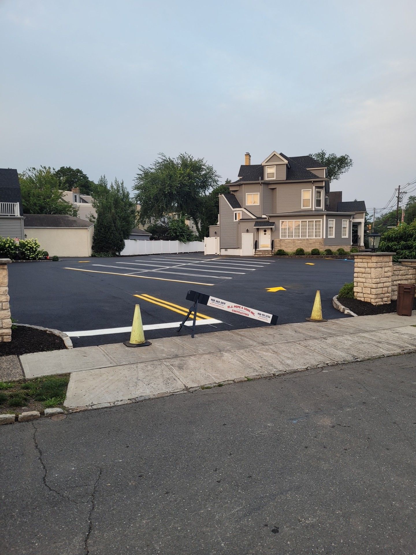 A parking lot with cones and a house in the background.