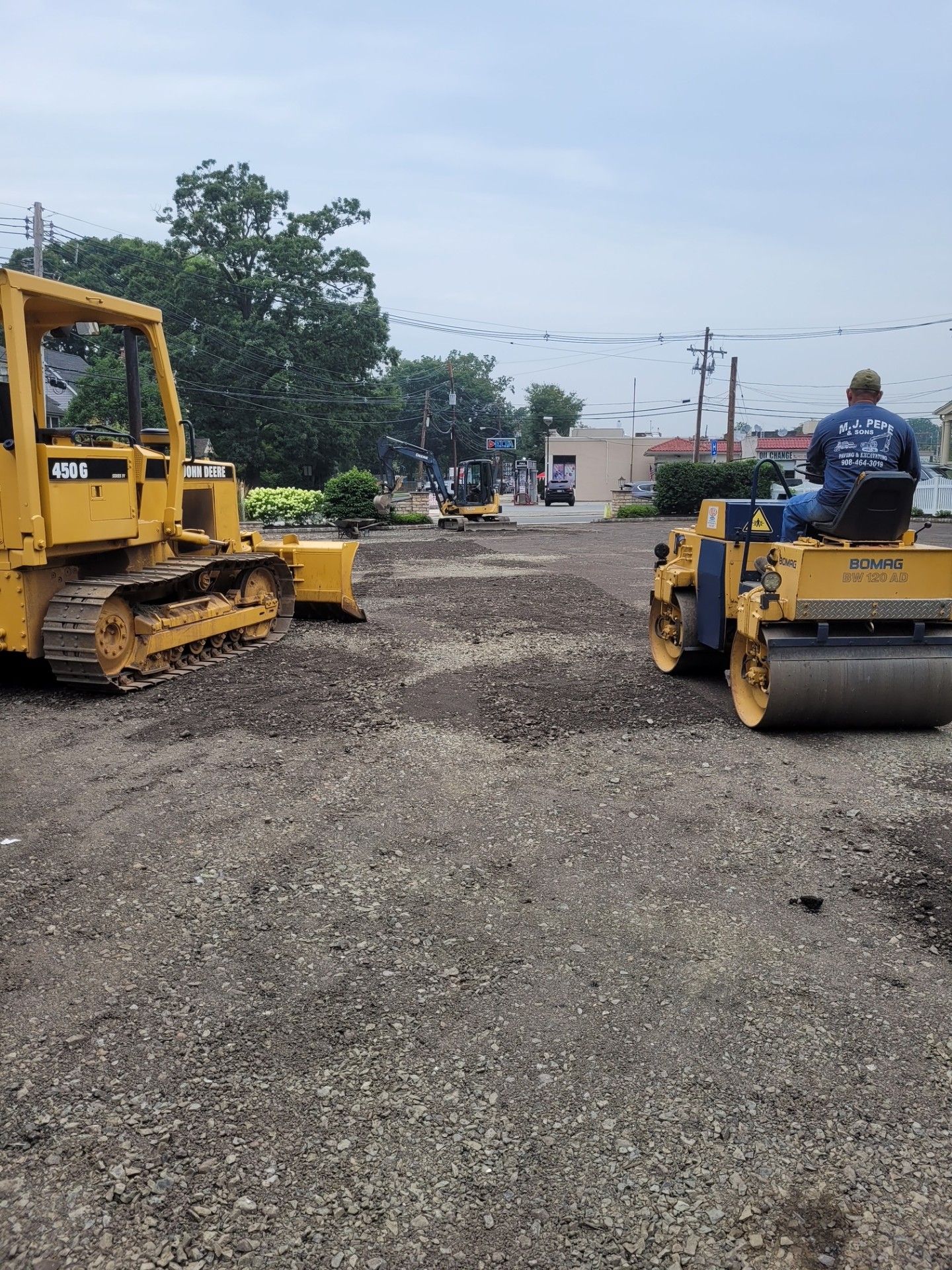 A bulldozer and a roller are sitting in a gravel lot.