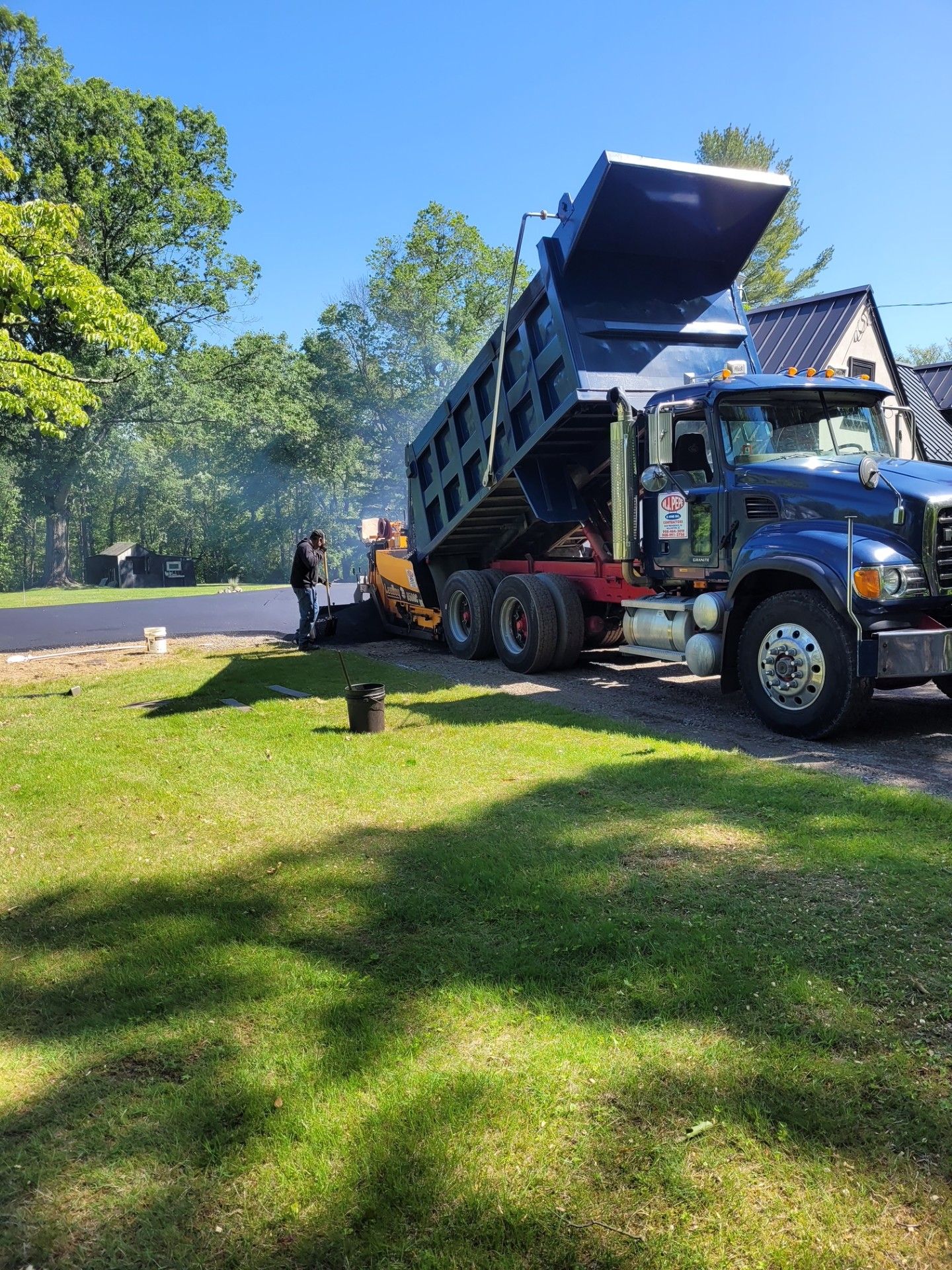 A dump truck is parked in a grassy area next to a house.