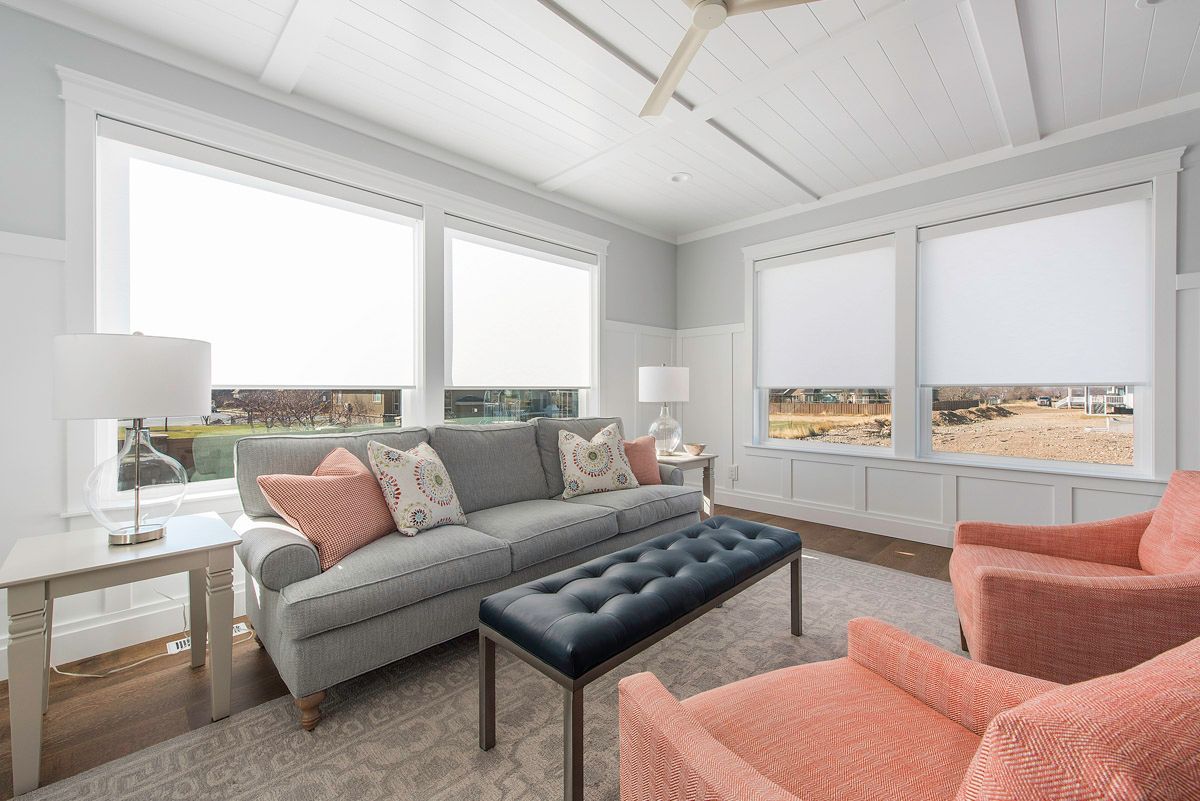 A living room with a couch , chairs , a table and a ceiling fan.
