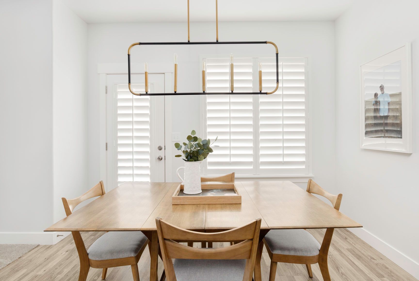 A dining room with a wooden table and chairs and a chandelier.
