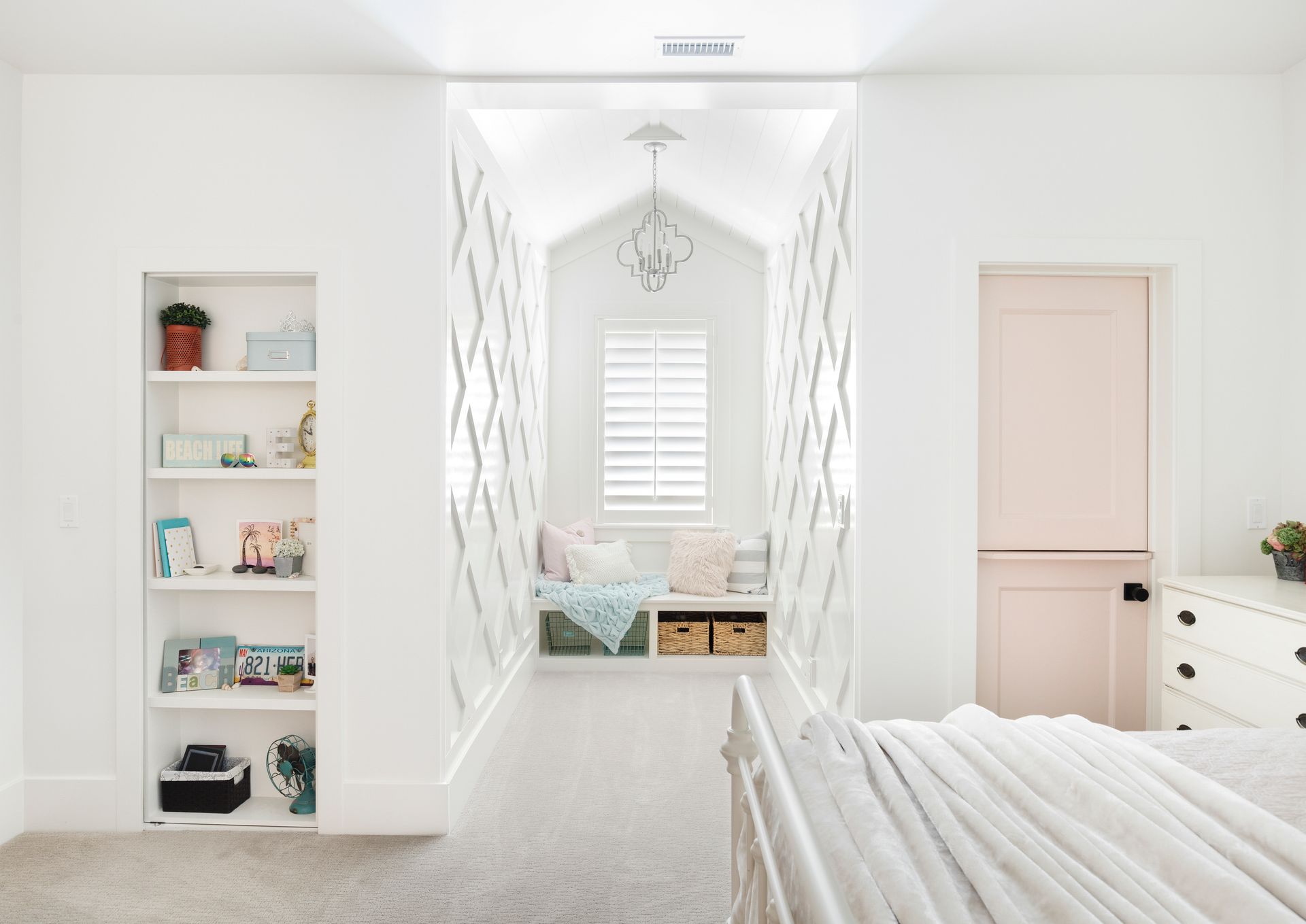 A bedroom with a bed , shelves , and a window seat.