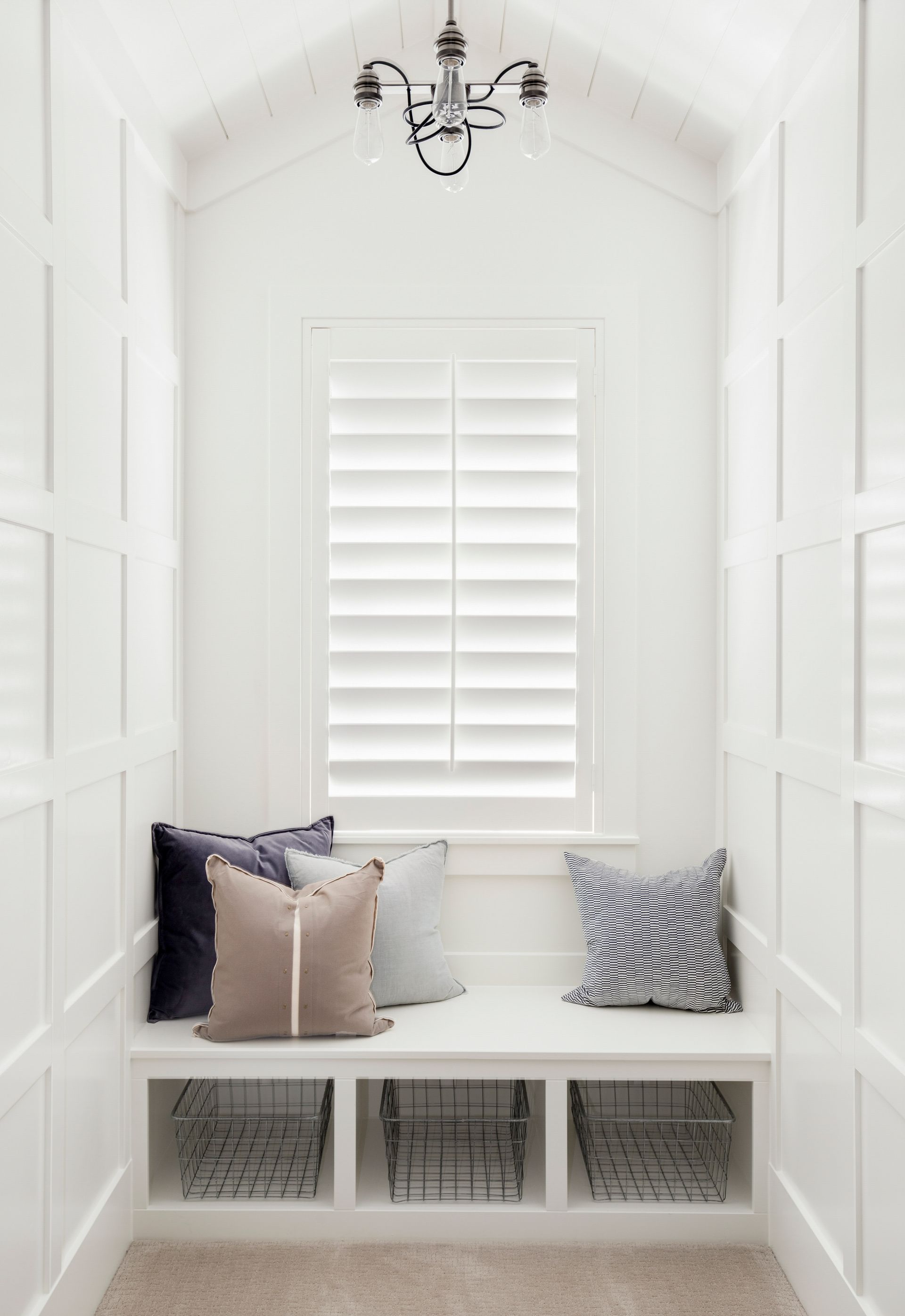 A room with a window and a bench with pillows on it
