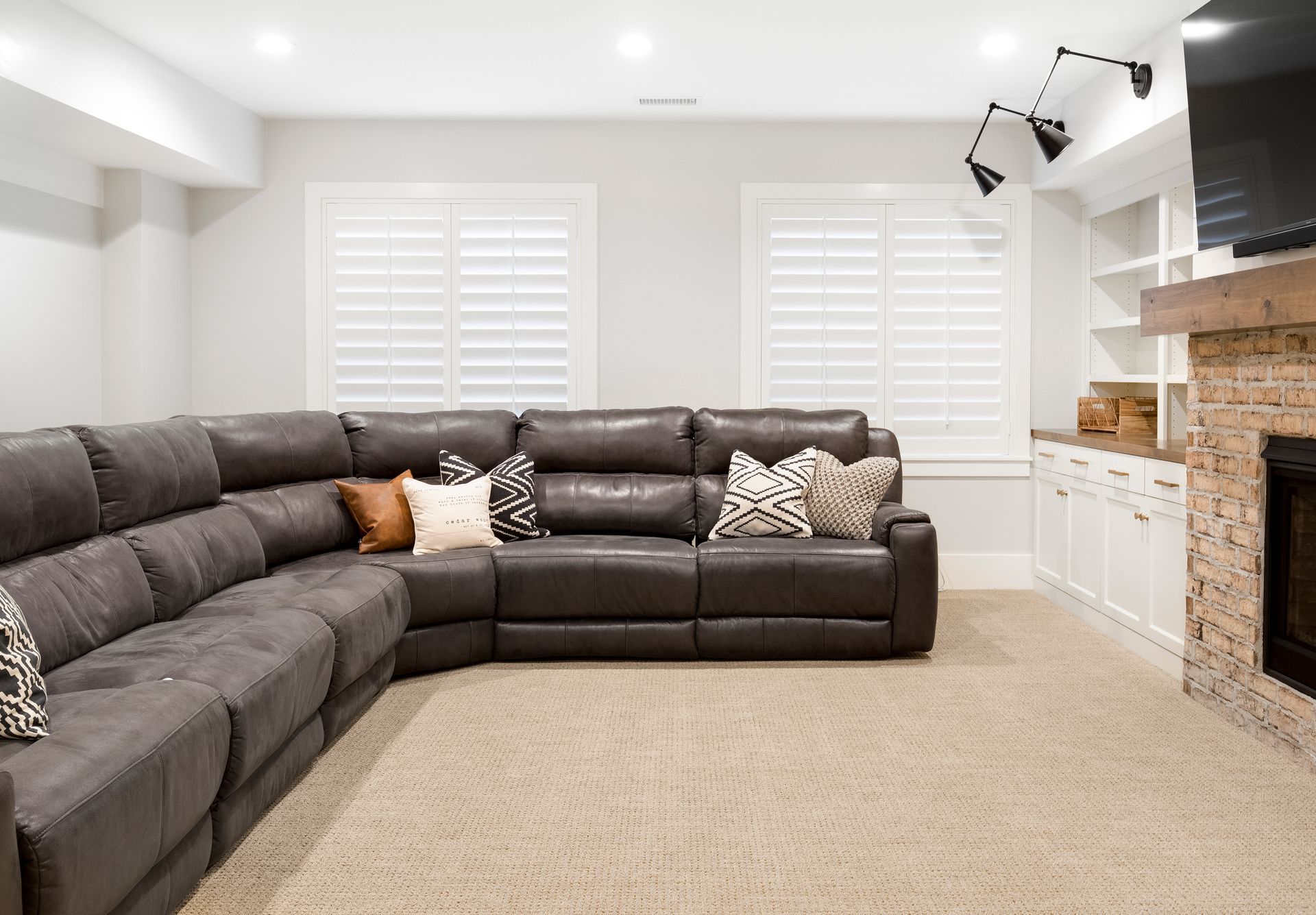 A living room with a large sectional couch and a fireplace.