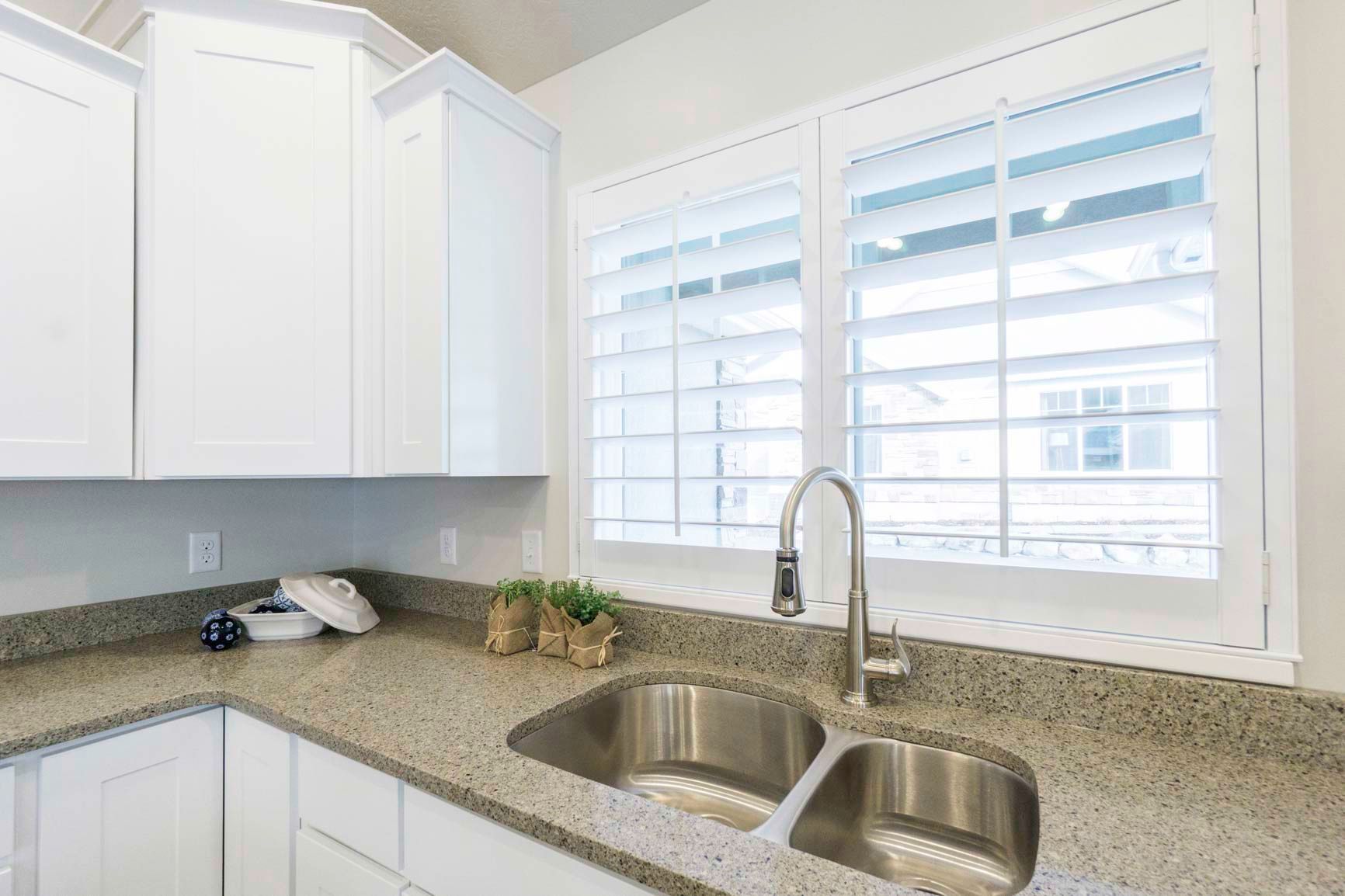 A kitchen with a sink and a window with shutters.