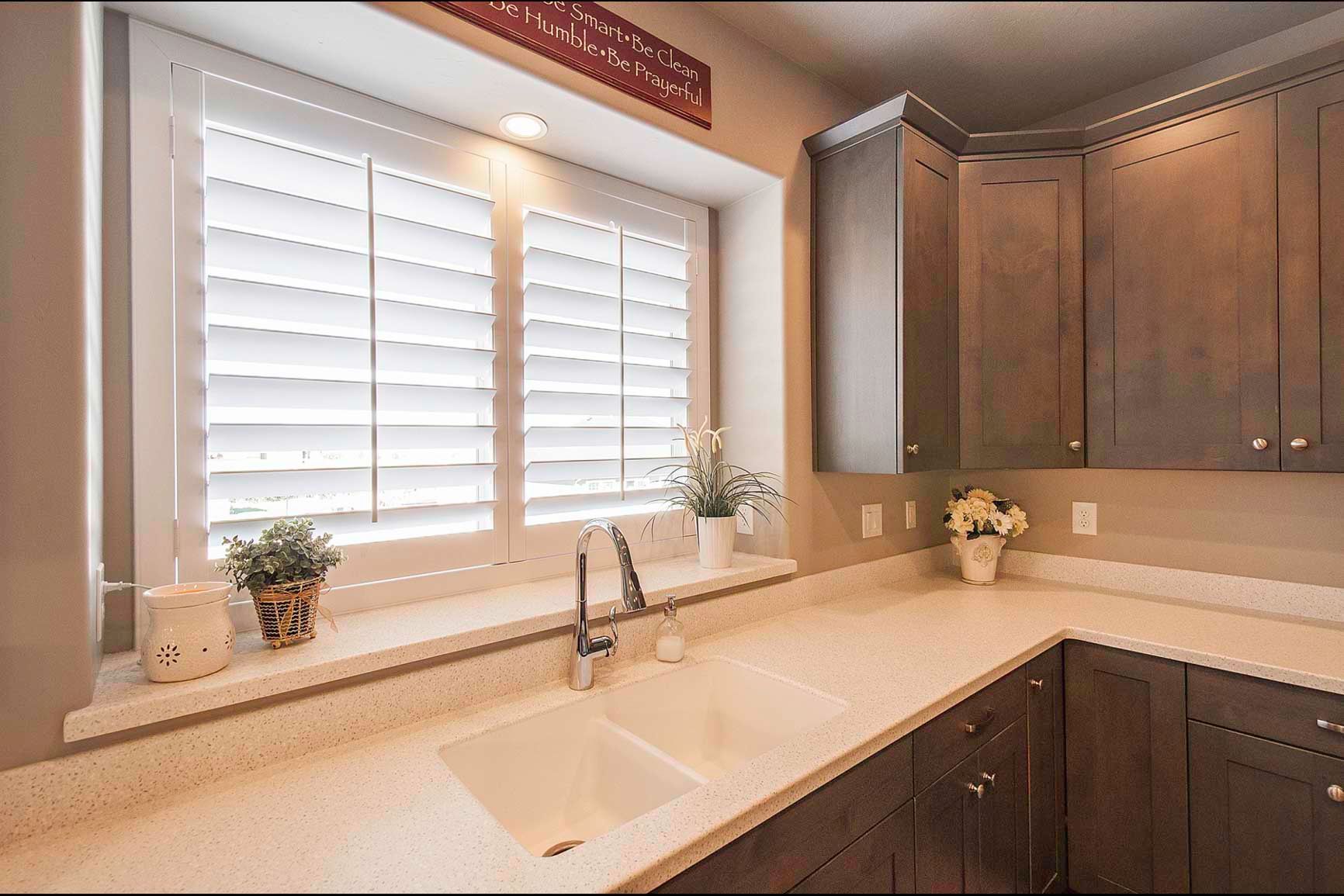 A kitchen with a sink and a window with shutters.