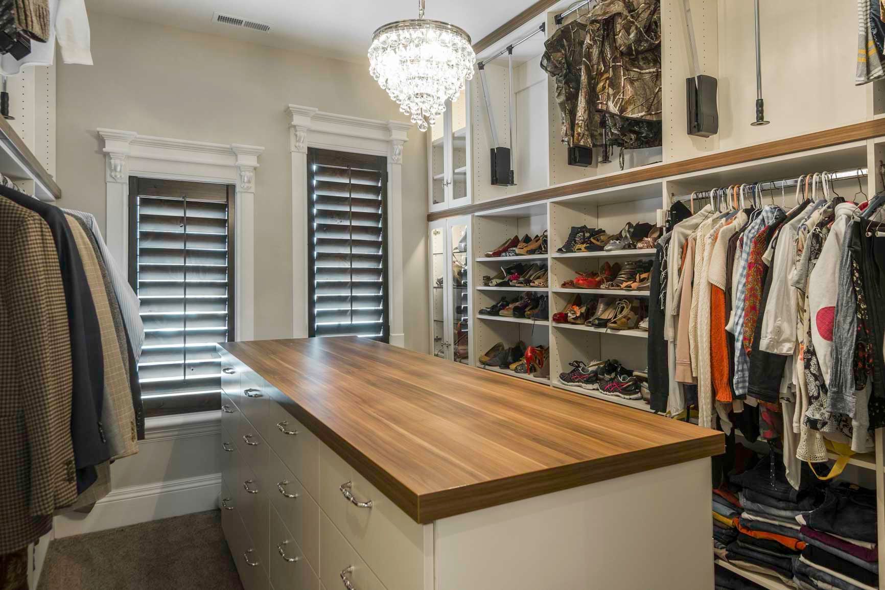 A walk in closet with a large wooden island in the middle.