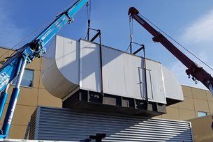 A large piece of equipment is being lifted by a crane.